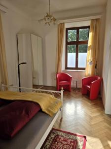 a bedroom with a bed and two red chairs at Apartment Geidorf in Graz