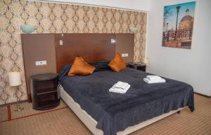 una camera da letto con un grande letto con lenzuola blu e cuscini arancioni di Hotel Parc a Onești