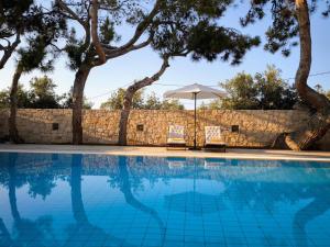 une piscine avec deux chaises et un parasol dans l'établissement Villa Phos, à Gouves