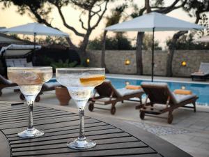 deux verres à vin posés sur une table près d'une piscine dans l'établissement Villa Phos, à Gouves