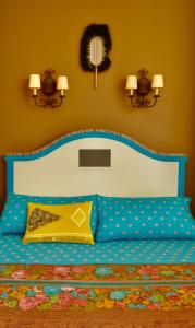 een slaapkamer met een blauw bed en een geel kussen bij Centre historique de LYONS LA FORET Hotel de Maître le Cottage in Lyons-la-Forêt