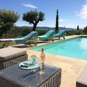 a bottle of wine sitting on a table next to a pool at Villa "La vie est belle...!" in Cavalaire-sur-Mer