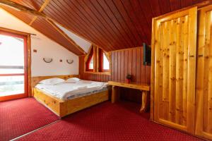 ein Schlafzimmer mit einem Bett in einem Holzzimmer in der Unterkunft Pensiunea Alpin SPA in Ranca