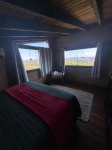 a bedroom with a bed and two windows with a view at Chalé Alto da Copaiba in Cunha