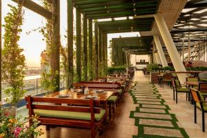 een restaurant met houten tafels, stoelen en planten bij Aloft Abu Dhabi in Abu Dhabi