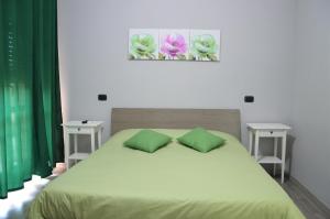 Schlafzimmer mit einem Bett mit grüner Bettwäsche und grünen Kissen in der Unterkunft Iris Inn in Salerno