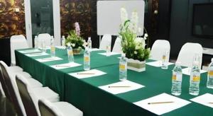 een lange groene tafel met witte stoelen en flessen water bij 900 Inn in Bintulu