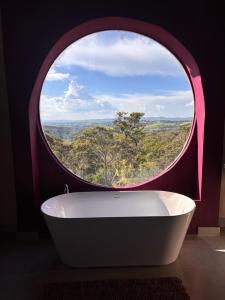 a round window in a bathroom with a bath tub at O Canto das Fadas Chalés in São Thomé das Letras