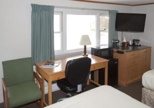 ein Hotelzimmer mit einem Schreibtisch, einem Stuhl und einem Bett in der Unterkunft The Bluebird Motel Maine in Machias