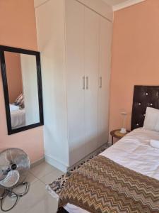 a bedroom with a bed and a mirror and a fan at Dulelo Serowe in Serowe