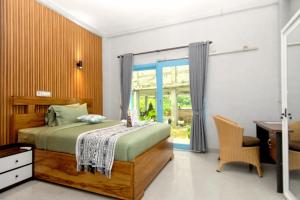 een slaapkamer met een bed, een bureau en een raam bij Hotel Bonne Nuit in Labuan Bajo