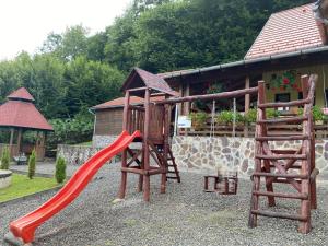 een speeltuin met een rode glijbaan en een houten speelplaats bij Pensiunea Jazmin in Zetea