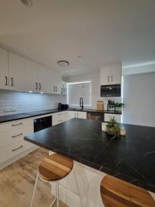 a kitchen with white cabinets and a black counter top at Sheik Oasis in Lightning Ridge