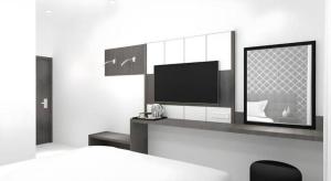 a bedroom with a tv and a bed and a desk at Smart Budget Hotel in Stasiun Tawang