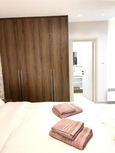 due asciugamani seduti sopra un letto bianco di Iris Apartment II Livadeia a Levádeia Altre 11 foto