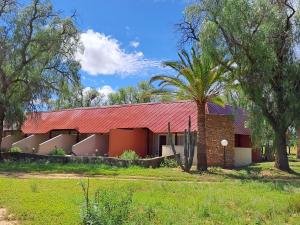 a house with a red roof and a palm tree at Auas Safari Lodge in Windhoek
