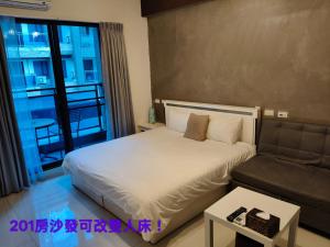ein Schlafzimmer mit einem weißen Bett und einer Couch in der Unterkunft Fun B&B in Altstadt von Hengchun