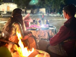 een man en een vrouw die rond een tafel zitten met een vuur bij Saraiville- A Boutique Riverside Resort in Dehradun +91 foto's