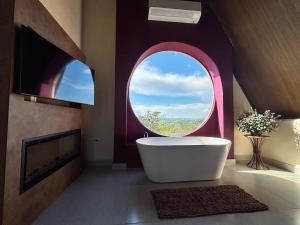 a bathroom with a tub and a round window at O Canto das Fadas Chalés in São Thomé das Letras