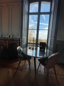 ein Tisch und Stühle in einem Raum mit einem großen Fenster in der Unterkunft Château de Savonnières in La Bruère-sur-Loir