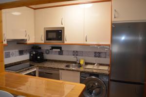 a kitchen with white cabinets and a stainless steel refrigerator at JayjAstur in Cangas de Onís