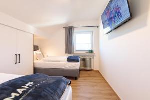 a bedroom with two beds and a tv on the wall at Heu22 Heuboden in Farchant