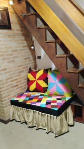 a couch with colorful pillows sitting under a staircase at Beco do Curupira Bangalô in São Luiz do Paraitinga