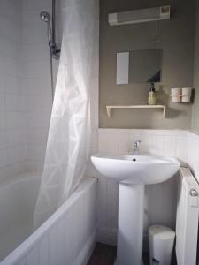 ein weißes Badezimmer mit Waschbecken und Badewanne in der Unterkunft Demeure périgourdine, prairies et accès rivière in Cherveix-Cubas