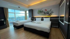 una camera d'albergo con due letti e una grande finestra di โรงแรมริเวอร์ ซิตี้ ปัตตานี a Ban Ru Sa Mi Lae Altre 63 foto