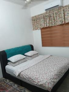 a bedroom with a bed with a green headboard and pillows at Shayus Homestay in Kampong Alor +1 photo