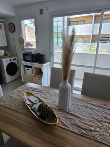 a dining room table with a vase with a plate of food at Peperina 2 villa Carlos paz in Villa Carlos Paz +2 photos