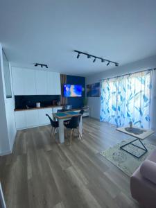 a living room with a table and chairs and a kitchen at Apartament SUNNY Rusinowo in Rusinowo