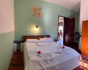 een slaapkamer met een bed met witte lakens en handdoeken bij Pousada Casa do Josef in Canoa Quebrada