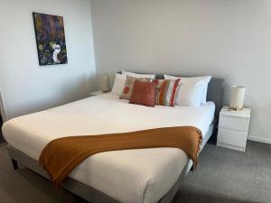 een slaapkamer met een groot wit bed met kussens bij Lake Views Belconnen in Belconnen