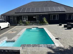 a swimming pool with solar panels on top of a house at Bell rose oaks guest house in Blomtuin