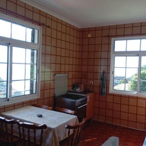 a kitchen with a table and two windows at Yellow Owl II - Bedroom III in Campanário +11 photos