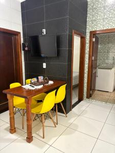 een eetkamer met een houten tafel en gele stoelen bij Pousada Paraíso Central - Casinha in Rodeio