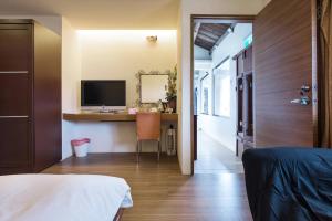 - une chambre avec un bureau, un ordinateur et un lit dans l'établissement Jiufen Breeze 九份惠風民宿ｌ6人包棟小屋, à Jiufen
