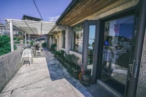 une terrasse extérieure avec des chaises et des tables et une porte vitrée dans l'établissement Jiufen Breeze 九份惠風民宿ｌ6人包棟小屋, à Jiufen