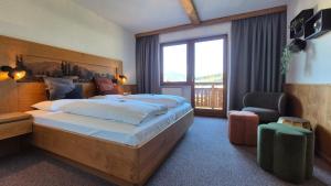 a bedroom with a large bed and a large window at Hotel Dahoam by Miha in Westendorf