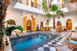 an indoor swimming pool in a house with a checkered floor at Riad LallaBaya in Marrakesh