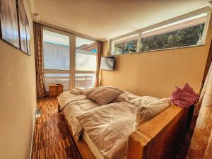 een bed in een kamer met twee ramen bij ALPENLOFT Gerlitzen Ski in - Ski out! in Kanzelhöhe