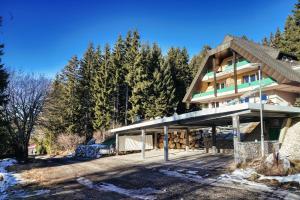 a large building with a porch in front of trees at ALPENLOFT vom Berg zum See inklusive gratis KärntenCard in Kanzelhöhe