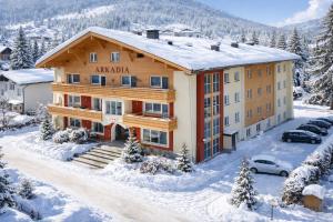 an apartment building in the snow with a parking lot at Arkadia Apartments in Bad Hofgastein