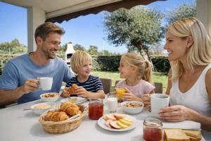 een gezin dat aan een tafel zit en ontbijt eet bij Ville d'Ogliastra 2 - Marina Suites in Cardedu