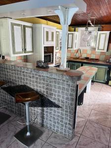 a kitchen with a counter with a stool in it at Fleur de Canne in Saint-Benoît +3 photos
