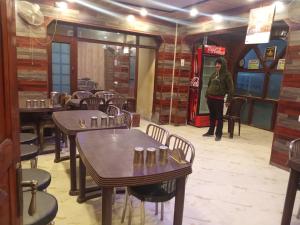 a woman standing in a restaurant with tables and chairs at Hotel taimoor in Srinagar