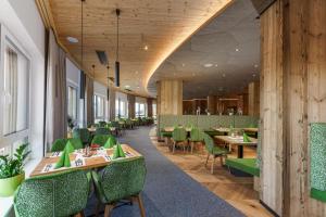 a dining room with tables and green chairs at Hotel Moser in Schladming