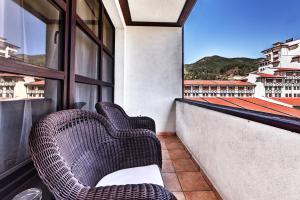 2 rieten stoelen op een balkon met uitzicht bij Спа Хотел Орфей in Devin