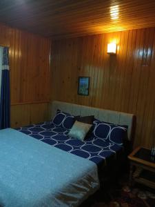 a bedroom with a blue bed with wooden walls at Ghising Newas Homestay in Jālāpahār